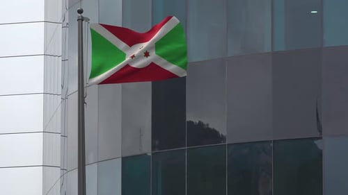 Burundi Flag Waving on Pole in Front of Glass Building
