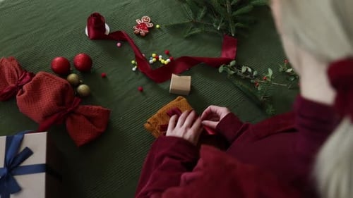 Woman Decorating Christmas Presents at Home