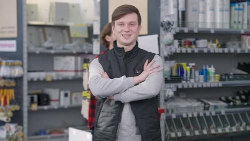 Middle Shot of Young Brunette Man Crossing Hands Looking at Camera Smiling As Male Buyer Passing at