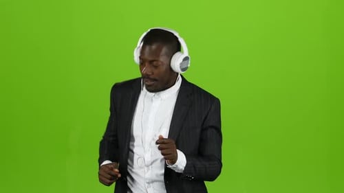 Businessman and Headphones on Ears, Listening To Music and Dancing on the Spot. Green Screen