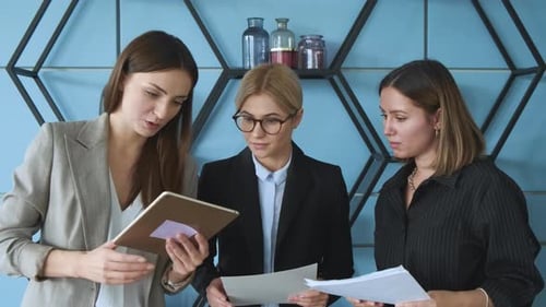Schöne Mädchen kommunizieren in der Pause bei der Arbeit. Drei Geschäftsfrauen diskutieren über die Arbeit