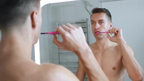 Man brushes teeth in modern bathroom, morning routine