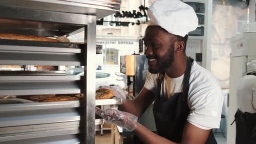 Baker Taking Fresh Pastries from the Oven
