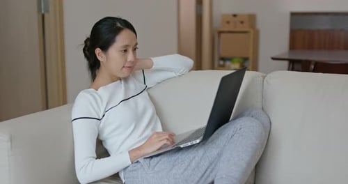 Woman Works on Laptop Relaxing on Couch Indoors
