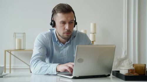Man Customer Service Operator in Headset at Workplace Manager Sitting at Desk with Laptop in Office
