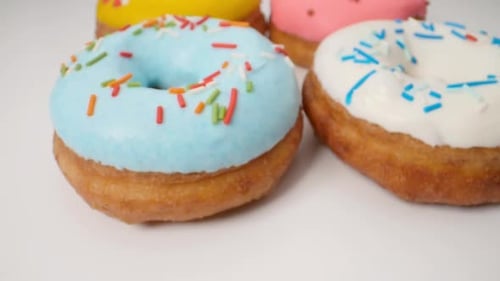 Köstliche mehrfarbige Donuts auf weißem Hintergrund. Sanfte Dolly Motion