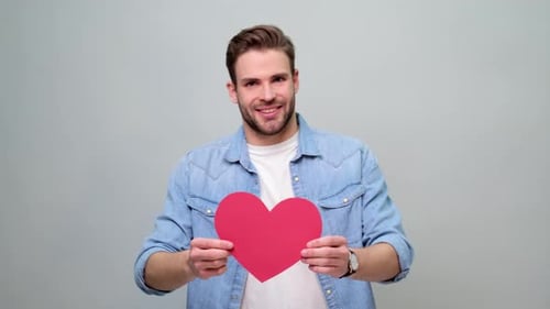 Man Holding Heart Shaped Card Smiling at Camera