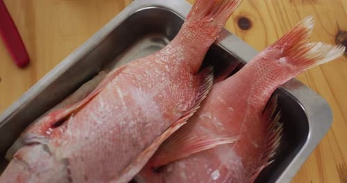 Two fishes lying in a pan, ready to be cooked