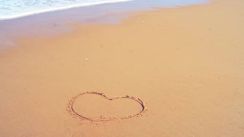 Herzform romantisch am Meer Strand und plätschernde Wellen im Sand mit der Zeitlupenwelle in n