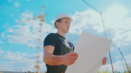 Construction Worker Examines Blueprints at Construction Site
