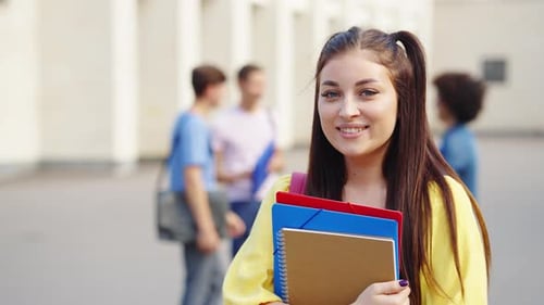 Female student with books smiling near college