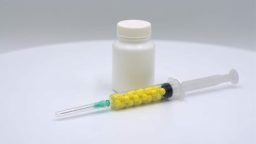 Syringe with Yellow Capsules and Medicine Bottle