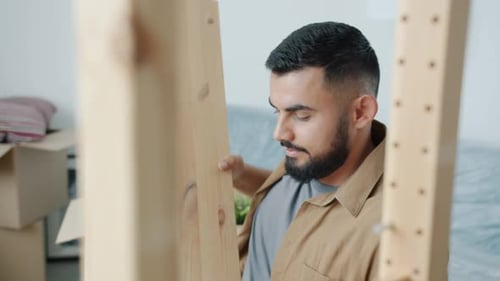 Man Assembling Wooden Shelving in Bright Room