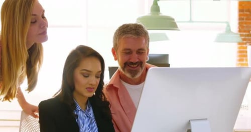 Colleagues Reviewing Computer Together in Modern Office
