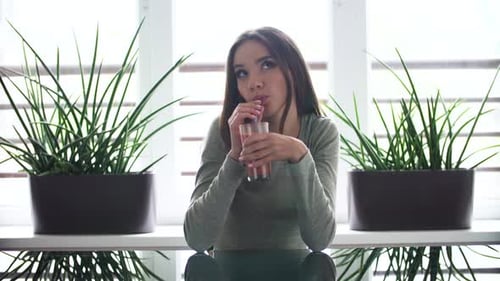 Smiling Woman Sipping Drink Indoors