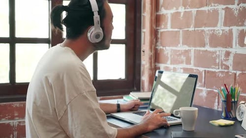 Young Adult Working on Laptop with Headphones