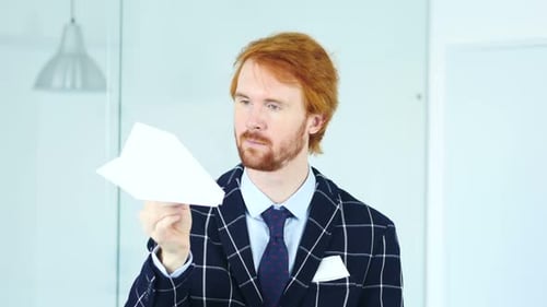 Man Holding Paper Airplane in Office Setting