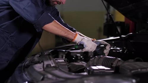 Automechaniker arbeitet mit Schraubenschlüssel unter der Motorhaube