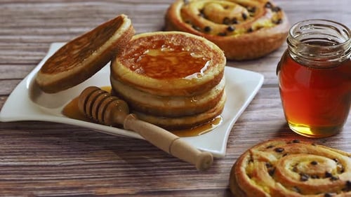 Pancakes with Honey and Pastries on Wood Table