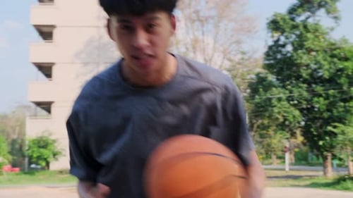 Young sports men practicing basketball on the outdoor court.