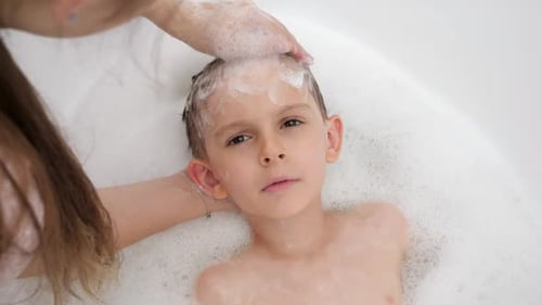 Smiling Boy Getting Hair Washed in Bathtub