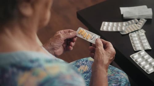 Senior Woman Examining Various Pills At Home