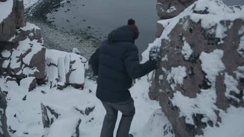 A Young Man Stands in a Cliff Gorge and Admires the View of the Dragon Eggs Beach on the Coast of