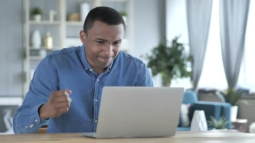 Frustrated Man Working on Laptop at Desk