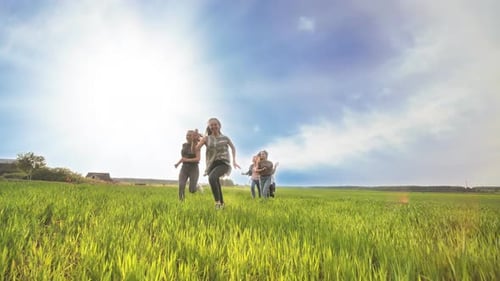 Happy Friends Run Against the Backdrop of a Beautiful Sky and Sun.
