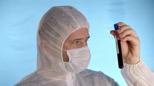 Man in protective suit, medical mask, gloves holds test tube with Coronovirus