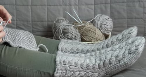 Person Knitting a Gray Wool Garment Indoors