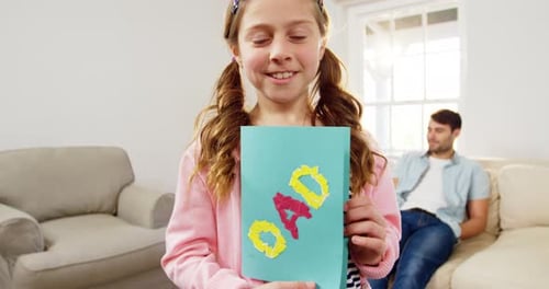 Girl Shows Handmade Birthday Card to her Father