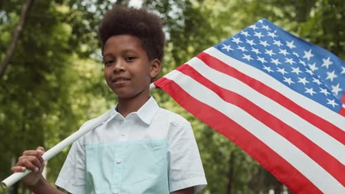 Boy Holding American Flag Smiling in Park