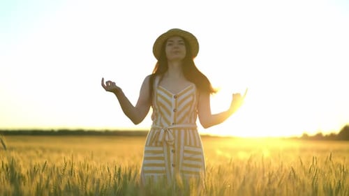 Woman Standing in Golden Wheat Field at Sunset