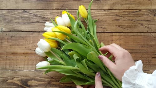 Put yellow and white tulips bouquet on a wooden table top view