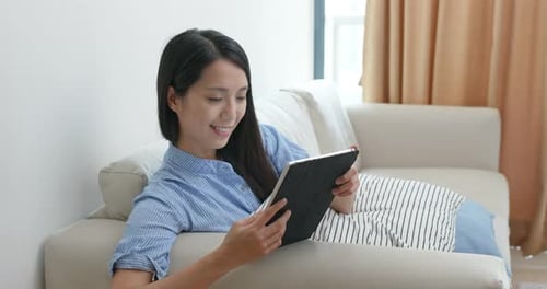 Woman Relaxes on Couch Using Tablet Device