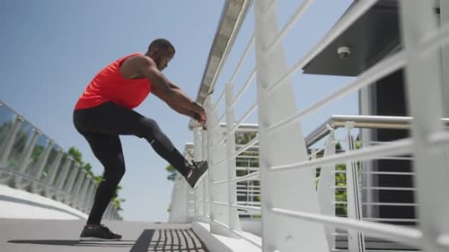 Young Man Stretching Leg on Bridge During Day