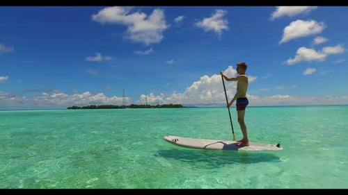 Young couple posing on tropical seashore beach lifestyle by turquoise ocean with white sand backgrou