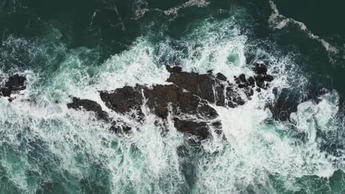 Aerial top view of rocks in the sea - Aerial video of majestic waves splashin