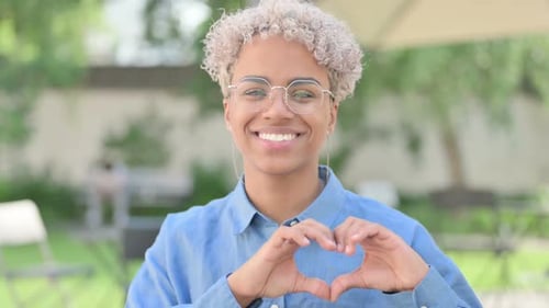 Smiling Woman Makes Heart Shape with Hands