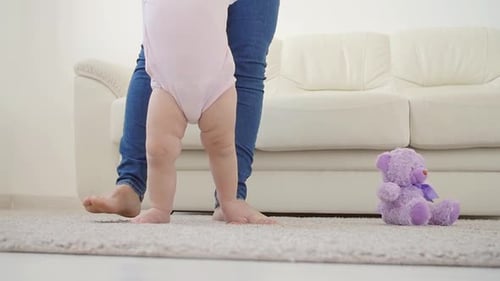 Baby Taking First Steps with Mother's Help at Home