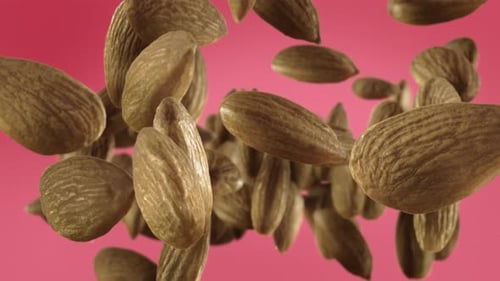 Dynamic Realistic Almonds Falling Against Pink Background