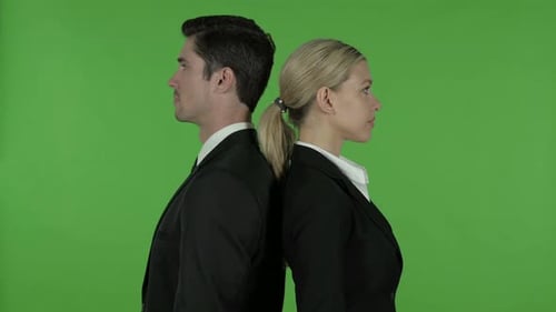 Joven profesional masculino y femenino de pie con los brazos cruzados y de espaldas el uno al otro Chroma Key