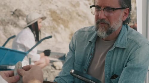 Arqueólogo masculino habla sobre la piedra con un colega