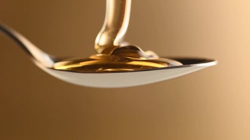 Thick honey dripping in spoon. Slow Motion.