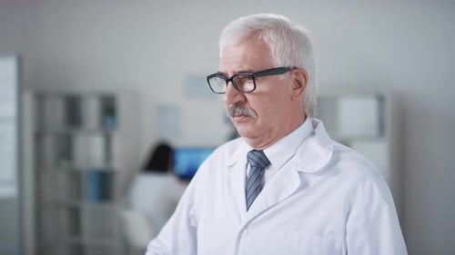 Senior Doctor Puts on Stethoscope in Clinic