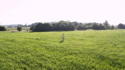 Man Stands on a Green Field
