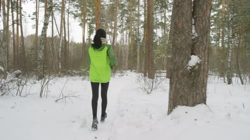 Rear View of Woman Running in Forest in Winter