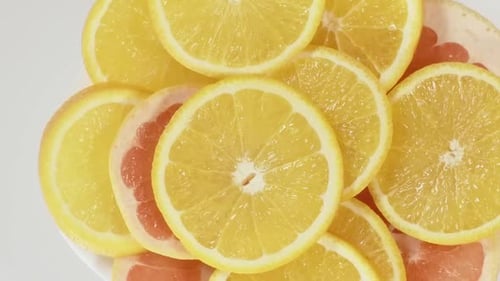 Bright Citrus Fruit Slices Rotating on White