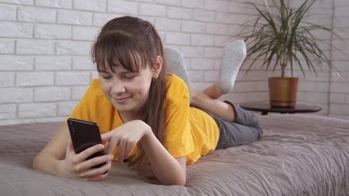 Teen Girl Using Smartphone on Bed